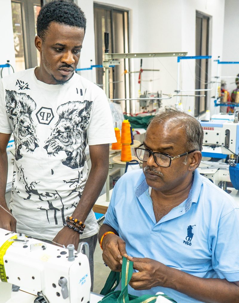 Two Kintela team members working through a garment detail beside a sewing machine