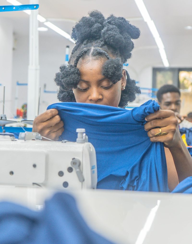 A Kintela team member examining blue fabric at her sewing workstation