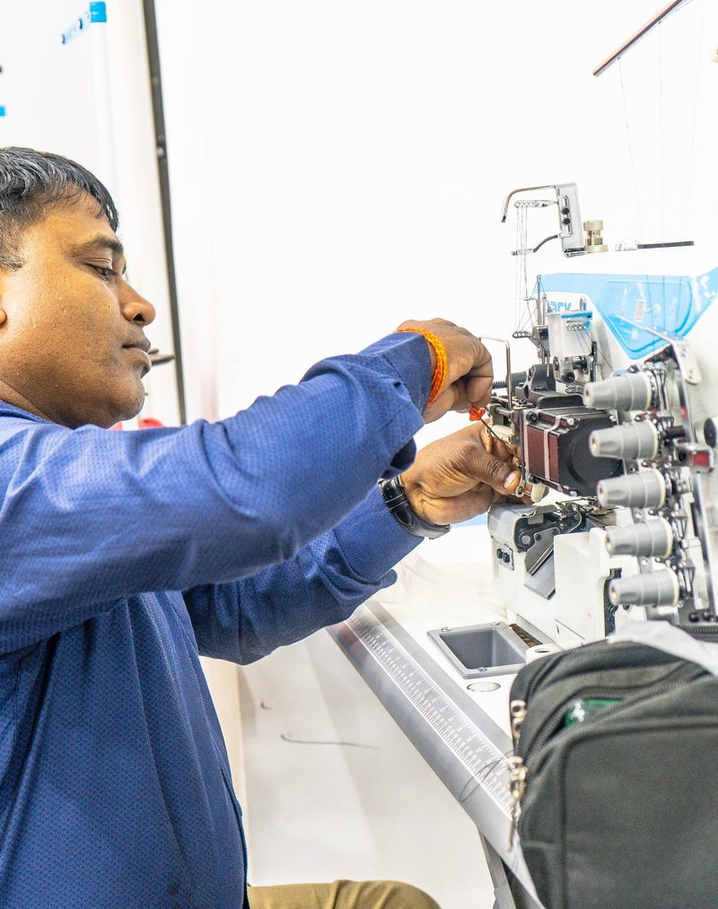 A Kintela team member adjusting the thread path on an overlock sewing machine